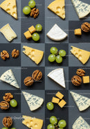 Assorted cheese wedges with grapes and walnuts on slate