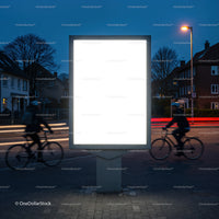 Urban illuminated billboard with motion blurred cyclists at dusk