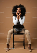 Thoughtful Woman Seated in Elegant Attire Against Brown Background