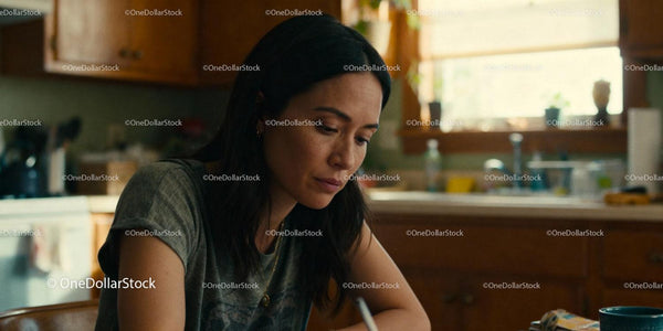 Thoughtful woman writing in warm sunlit kitchen