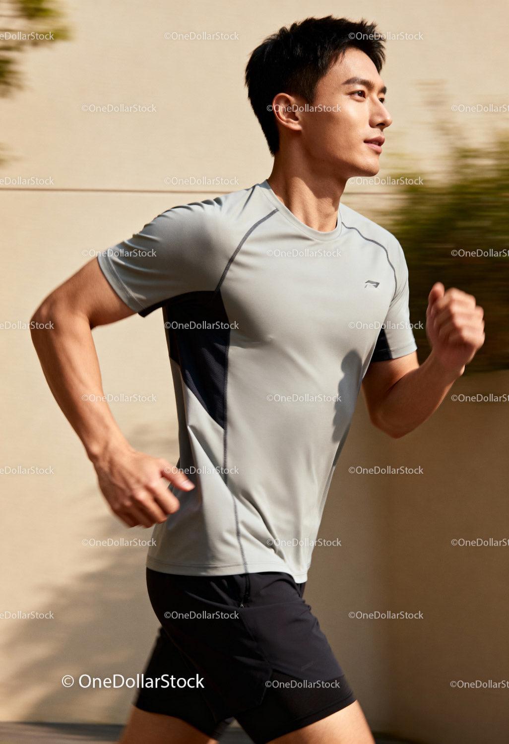 Focused young man jogging outdoors on sunny day