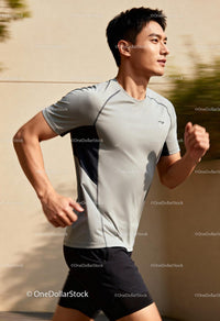 Focused young man jogging outdoors on sunny day