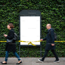 People Walking Past Empty Caution Taped Billboard Outdoors