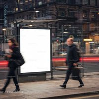 Blurred commuters walking past illuminated bus stop ad at dusk