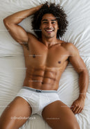Smiling muscular man relaxing on white bed in underwear