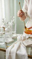 Elegant Glass Decanters and Cocktail with Orange Peel on Gold Spoon