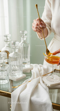 Elegant Glass Decanters and Cocktail with Orange Peel on Gold Spoon