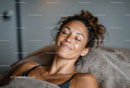 Relaxed Woman Smiling with Eyes Closed in Cozy Indoor Setting