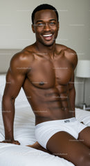 Smiling muscular man relaxing on bed in white underwear