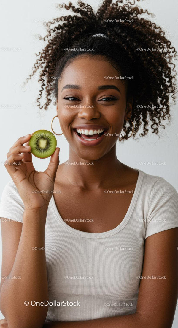 Joyful Young Woman with Curly Hair Holding Kiwi Slice with Bright Smile