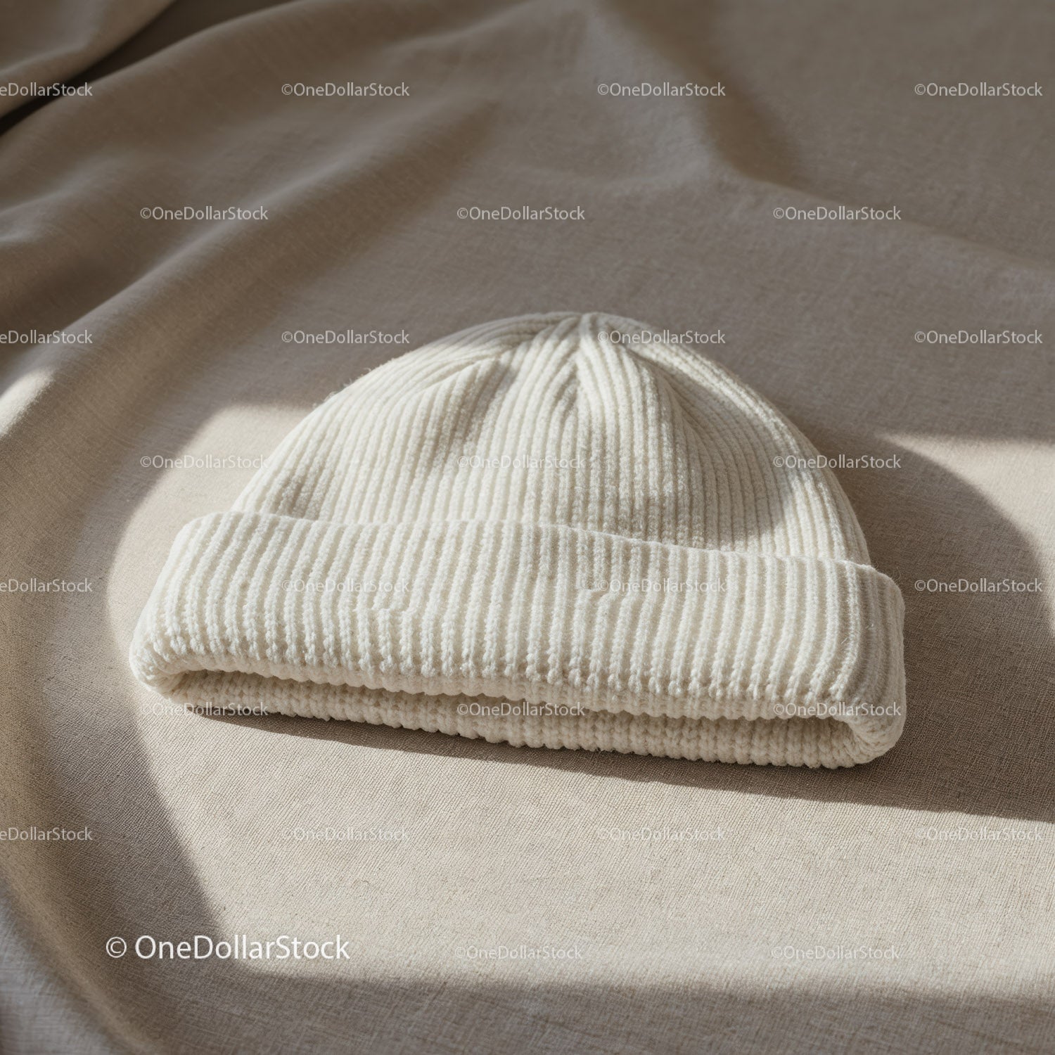Przytulna, biała, dzianinowa czapka beanie na beżowej powierzchni materiału