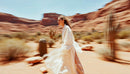 Elegant Model in Flowing Dress Walking Through Desert Landscape