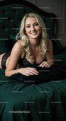 Smiling Blonde Woman Relaxing on Dark Green Bed