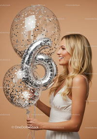 Smiling woman holding silver number six balloons