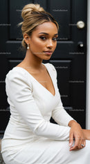 Elegant woman in white dress sitting by black door