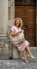 Smiling woman in pink dress with market bag outdoors