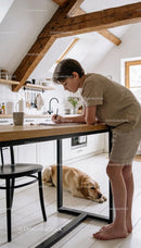Boy Leaning on Table Writing with Dog Resting Nearby