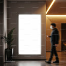 Man walking past illuminated blank poster in modern interior