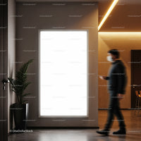 Man walking past illuminated blank poster in modern interior