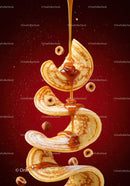 Golden syrup drizzling on flying pancakes with hazelnuts