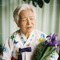 Elderly woman in traditional dress holding purple irises