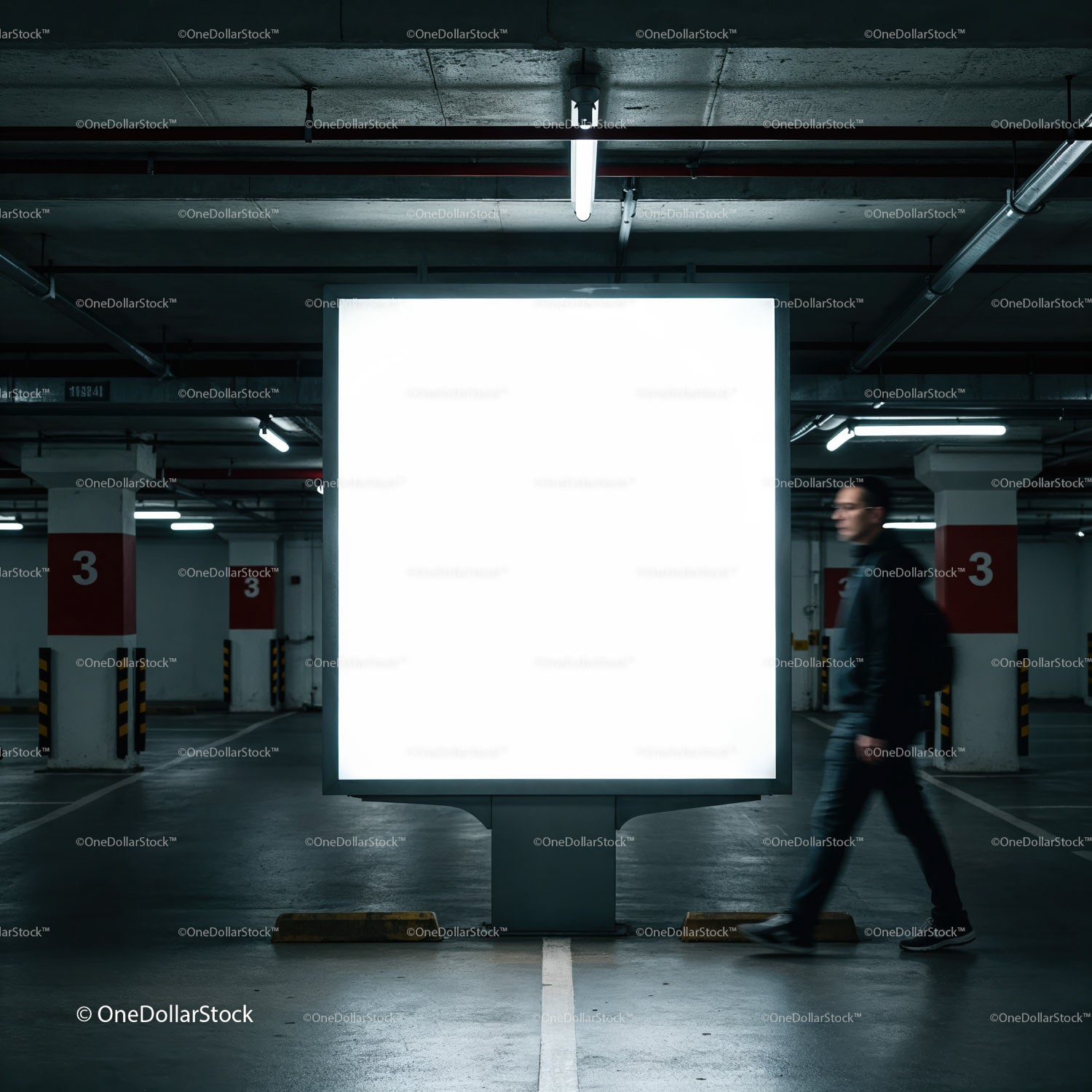 Mężczyzna przechodzi obok pustego, oświetlonego billboardu w garażu parkingowym