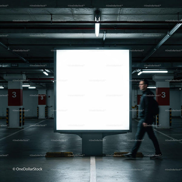 Man walking past blank illuminated billboard in parking garage JPG Mockup Image