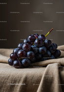 Fresh black grapes resting on textured fabric surface