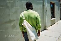 Urban Street Scene with Man in Green Sweater and White Tote Bag