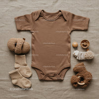 Neutral toned baby clothing and soft toys flat lay