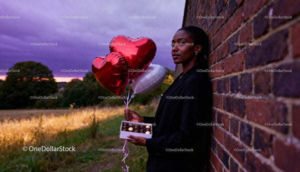 Woman Holding Heart Balloons and Chocolates at Sunset