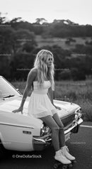 Young woman in white dress sitting on vintage car