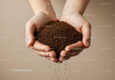 Hands holding and sifting coffee granules gently