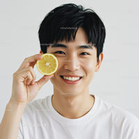 Young Smiling Asian Man Holding Lemon Slice on White Background