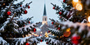 Snow-covered Christmas trees with red baubles near church