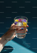 Hand Holding Floral Ice Water with Fresh Herbs