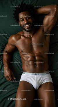 Smiling muscular man relaxing on dark green bed linens