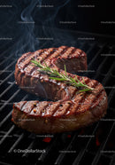 Juicy grilled steak with rosemary on barbecue grill