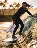 Young woman surfing a glowing wave at sunset