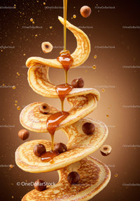 Golden syrup drizzling over spiraled pancakes with hazelnuts