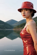 Stylish Woman in Red Satin Dress and Hat By Tranquil Lake