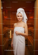 Young Woman Relaxing in Wooden Sauna with Towel Wrapped Hair