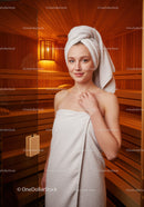 Young Woman Relaxing in Sauna with Towel in Wellness Center