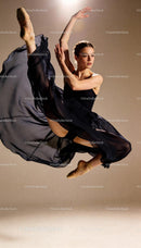 Graceful ballerina performing a high leap in black dress
