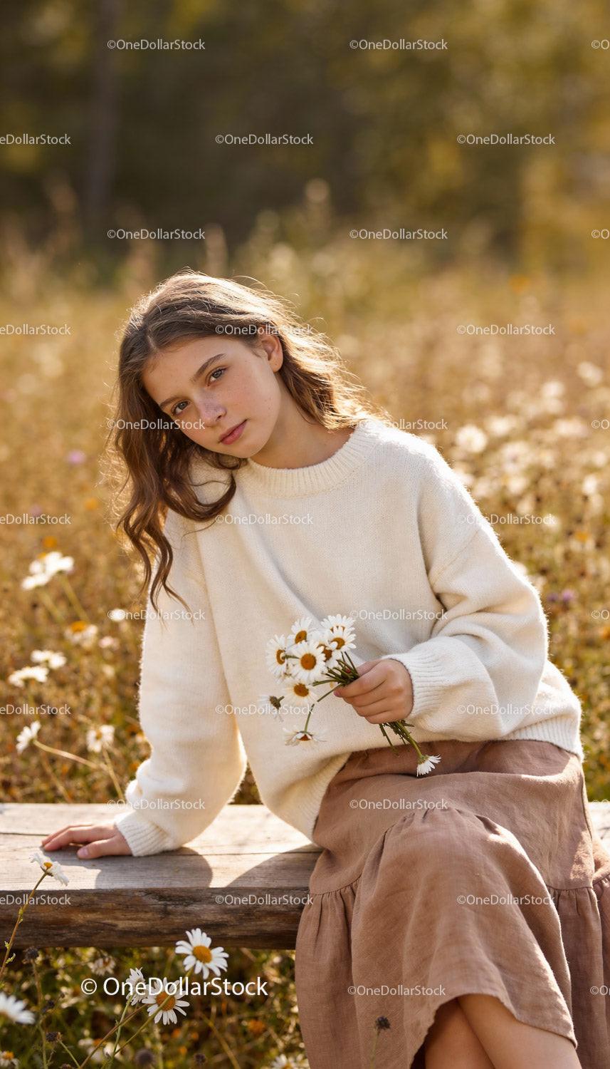 Young girl holding daisies in peaceful autumn field