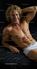 Smiling muscular man relaxing on black bed linen