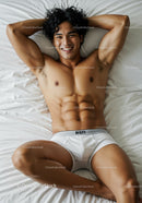 Smiling fit man relaxing in white underwear on bed