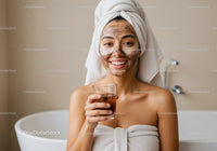 Young Woman with Facial Mask and Towel on Head in Bathroom