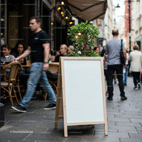 Outdoor café street scene with blank sidewalk signboard