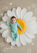 Smiling baby lying on large white daisy flower mat